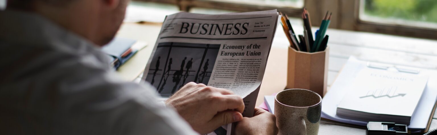 Businesspeople Reading Newspaper at Office Updating News